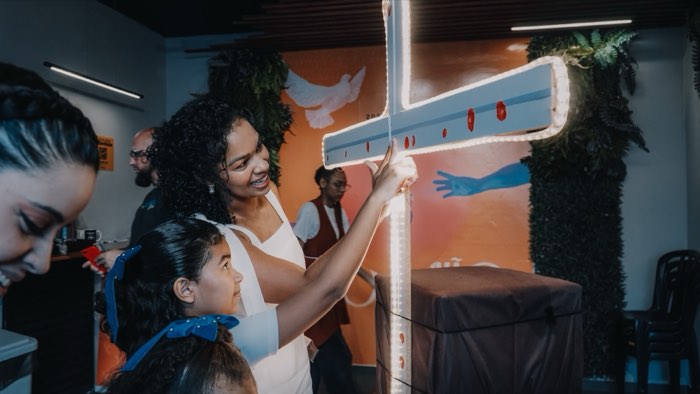 Família diante da cruz iluminada na recepção